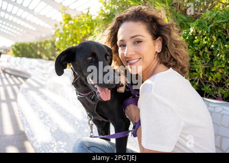 beautiful young woman with short curly hair with her dog outdoors Stock Photo