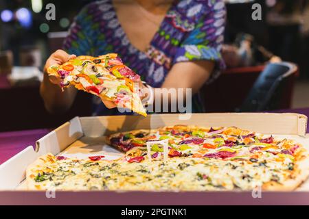 Woman hand taking a slice of New York pizza in takeaway box. Stock Photo