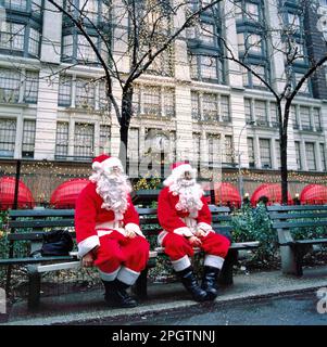 NEW YORK,USA-DECEMBER 23, 2018: Two people working as Santa Claus having a break at a park bench Stock Photo