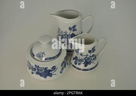 Complete set of milk and sugar service on a white background. Beautiful white dinner service with blue decoration isolated on white table. Milk pot cu Stock Photo