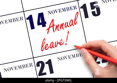 14th day of November. Hand writing the text ANNUAL LEAVE and drawing the sun on the calendar date November 14. Save the date. Time for the holidays. v Stock Photo