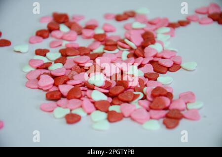 Small white, pink and red heart-shaped sweets to decorate a birthday cake Stock Photo
