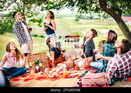 Fancy people laughing at vineyard place after sunset - Food and beverage concept with men and women drinking wine at barbeque party - Happy friends ca Stock Photo