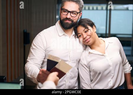 Young mixed-race romantic couple checking into hotel Stock Photo
