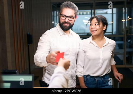 Happy couple getting keycard from front desk clerk Stock Photo