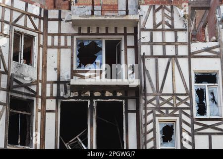 Destroyed building after russian invasion, Ukraine. Ruined facade of house with fachwerk design. War in Ukraine. Broken windows and brick walls. Stock Photo