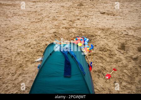 A beach tent with jeans drying and spades left outside in winter Stock Photo