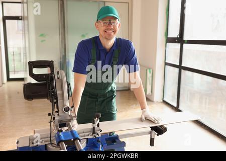 Worker cuts boards for parquet with sawing machine in room Stock Photo