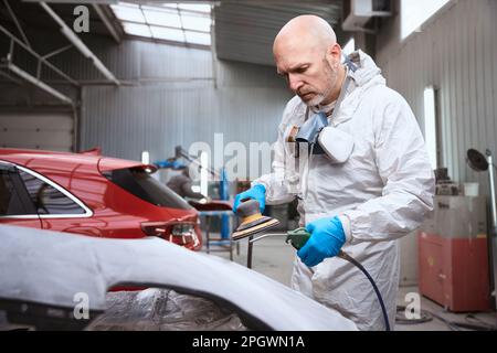 Auto repairman uses a pneumatic tool in process of grinding Stock Photo