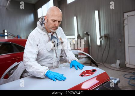 Auto repair shop worker working with unpainted car bumper Stock Photo