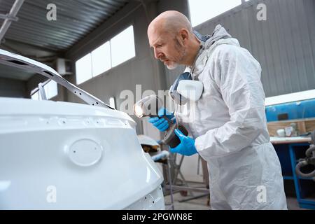 Painter uses a special flashlight to select paint for car Stock Photo