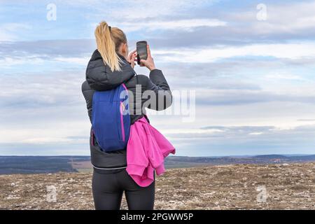 Sporty young blonde woman photographing landscape with mobile phone Stock Photo