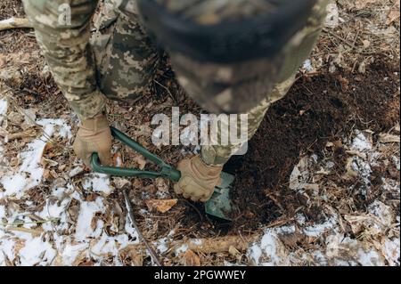 a soldier with a shovel in his hand digs the ground. Stock Photo