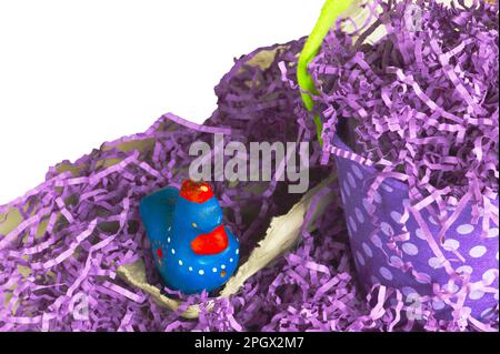 Easter grass with purple polkadot basket or pail placed by a chicken figure. Text space comes with image. Chicken is kitten on an egg carton. Stock Photo
