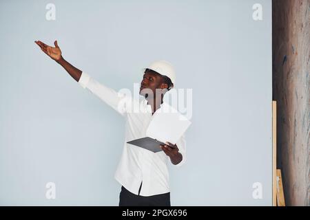 Young african american engineer in hardhat indoors with notepad in hands Stock Photo