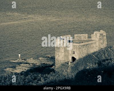 Black and White Landscape of Man Fishing at Little Dennis Fort, Pendennis Point, Falmouth, Cornwall, England, UK, GB. Stock Photo