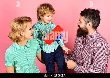Fathers day celebration. Cute son and mother greeting dad with present box. Happy family celebrating holiday together. Little child boy gives gift and Stock Photo