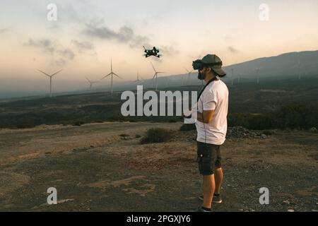 Drone engineer using first person view technology on the turbine farm - Alternative energy and aerial engineering concept Stock Photo