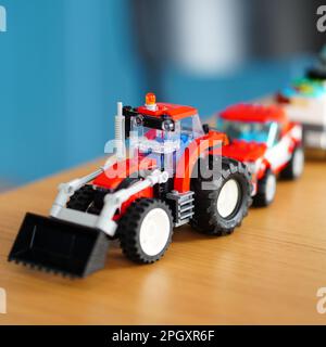 A selection of toy vehicles arranged neatly on a wooden table in front of a blue wall background Stock Photo