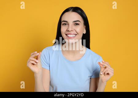 Young woman snapping fingers on yellow background Stock Photo