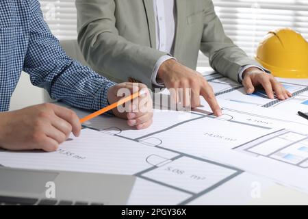Architects working with construction drawings at table in office, closeup Stock Photo