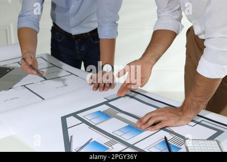 Architects working with construction drawings at table in office, closeup Stock Photo