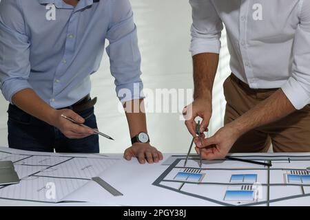 Architects working with construction drawings at table in office, closeup Stock Photo