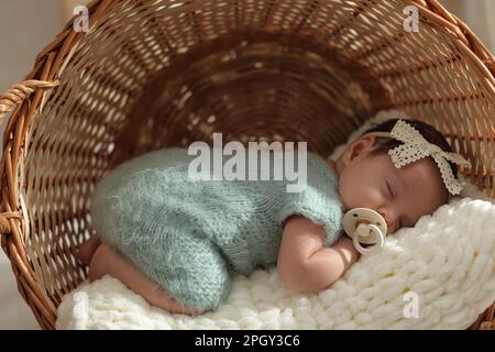 Adorable newborn baby with pacifier sleeping in wicker basket Stock Photo