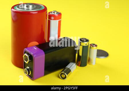 Different types of batteries on yellow background Stock Photo