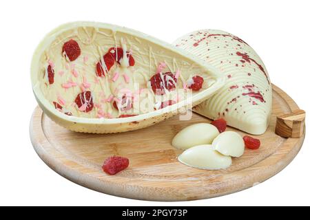A white chocolate Easter egg with candied strawberries on a wooden plate. Stock Photo