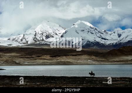 Looking up at Muztagh Tower, known as the father of glaciers, from Pamirs Karakul Lake Stock Photo