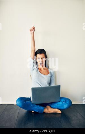 He poked me back. a young woman sitting on the floor while using a laptop. Stock Photo