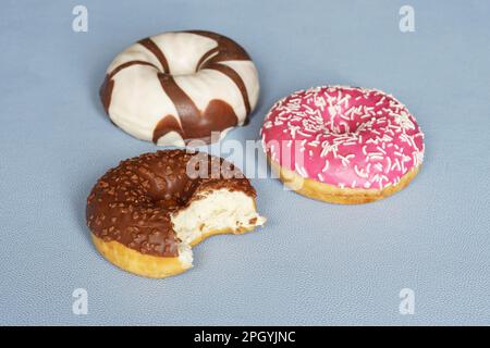donuts or doughnuts with different icing. chocolate donut missing a bite Stock Photo