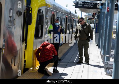 Santa Monica, California, USA. 25th Mar, 2023. A Santa Monica Police Officer and an LA Metro speak with a man needing medical attention on the Expo Line platform at Downtown Santa Monica Station.Homelessness, vagrancy and public drug use have plagued the LA Metro rail network since the 2020 COVID-19 pandemic, with ridership failing to return due to public safety concerns. Mass transit, car culture, infrastructure, esg. (Credit Image: © Taidgh Barron/ZUMA Press Wire) EDITORIAL USAGE ONLY! Not for Commercial USAGE! Stock Photo