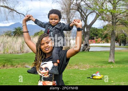 beautiful black mother carrying her son on her shoulders Stock Photo