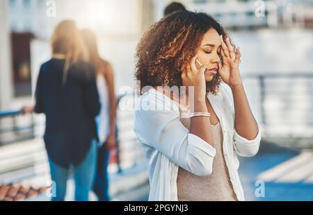 I cant deal with this right now. an attractive young woman looking stressed while making a phone call outside. Stock Photo
