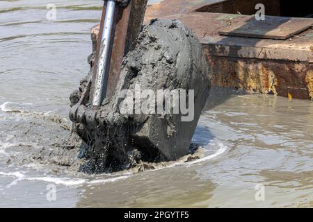 Dredging the bottom of water area, view of the bucket of the floating excavator full of mud Stock Photo