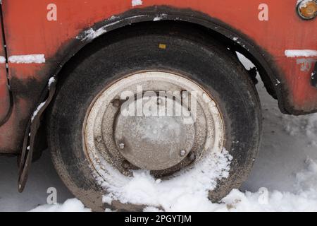 old car wheel in the snow on the road in winter close up Stock Photo