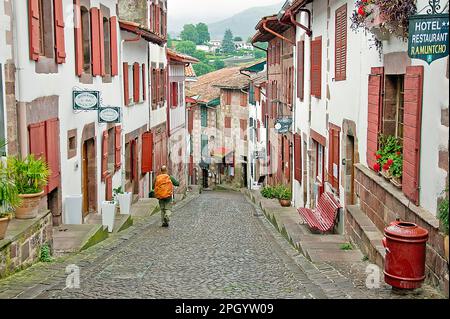A hiker on a street in St Jean Pied de Port, Basque country, France about to begin walking the Camino de Santiago. Stock Photo