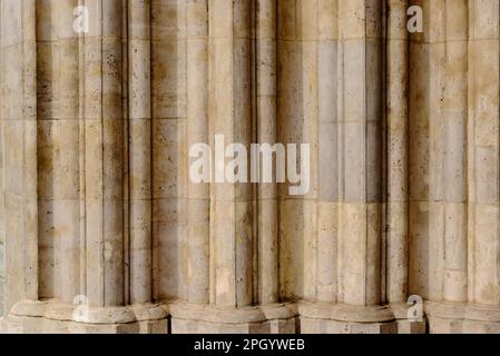 beautiful carved layered stone church door frame. richly decorated stone posts with ornate elements. neo gothic architecture. porous stone texture Stock Photo