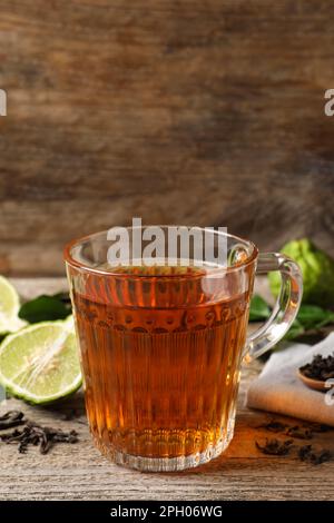 Glass cup of tasty bergamot tea, dry leaves and fresh fruits on white ...