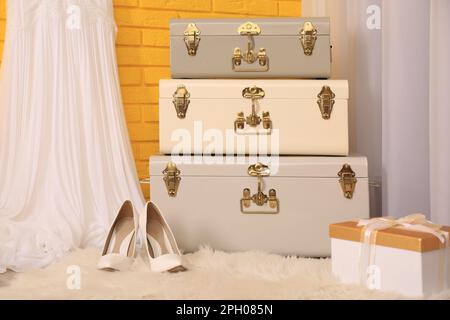 Storage trunks, shoes and gift box near yellow brick wall indoors. Interior design Stock Photo