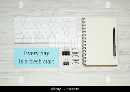 Note with motivational quote Every day is a fresh start, computer keyboard and office stationery on white wooden background, flat lay Stock Photo