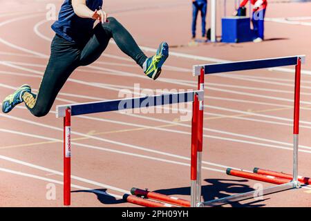 girl athlete run hurdles track and field race, Asics running spikes shoes, Polanik competition hurdles, sports editorial photo Stock Photo