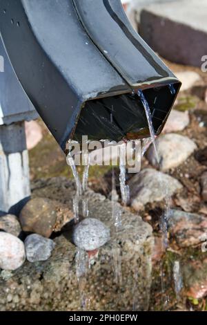 water flowing from a metal downspout in the springtime Stock Photo