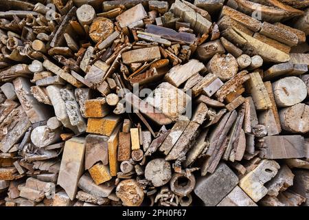 Background from stacked wooden boards of different shapes. Full surface texture of end pieces of wood pieces in shades of brown. Stock Photo