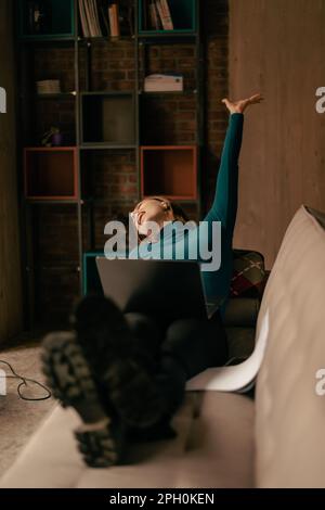 Excited girl waving her hands up and feeling relieved after she finished her online exam successfully at the coffee shop Stock Photo