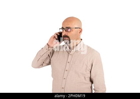 Portrait of middle aged bald man have phone conversation. Seriously listening, wearing glasses, looking at copy space, isolated on white. Stock Photo