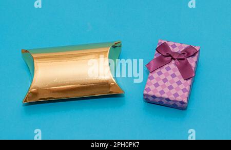 Decorative closed gold and purple festive gift boxes isolated on blue background Stock Photo
