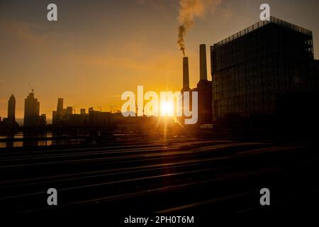 A smoking chimney on the silhouetted Battersea Power Station at dawn Stock Photo